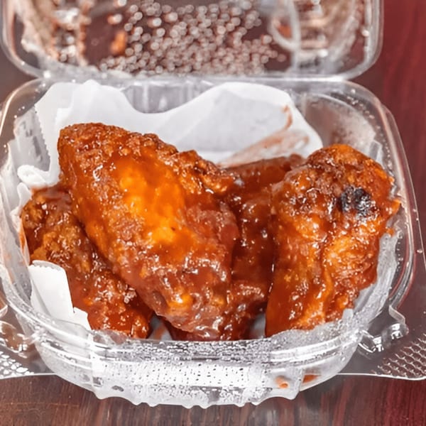 AlBasha Subs' chicken wings, coated in a glossy, reddish-brown sauce, served in a clear plastic container.