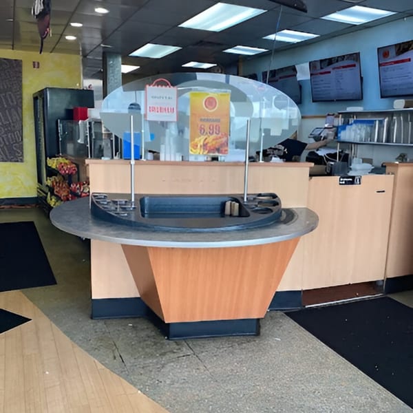 Interior view of AlBasha Subs, showing a condiment station, menu boards, and a counter.