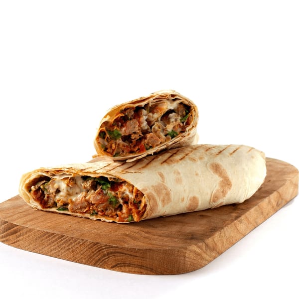 Two AlBasha Subs shawarma wraps, one cut in half, revealing meat and sauce on a wooden board.